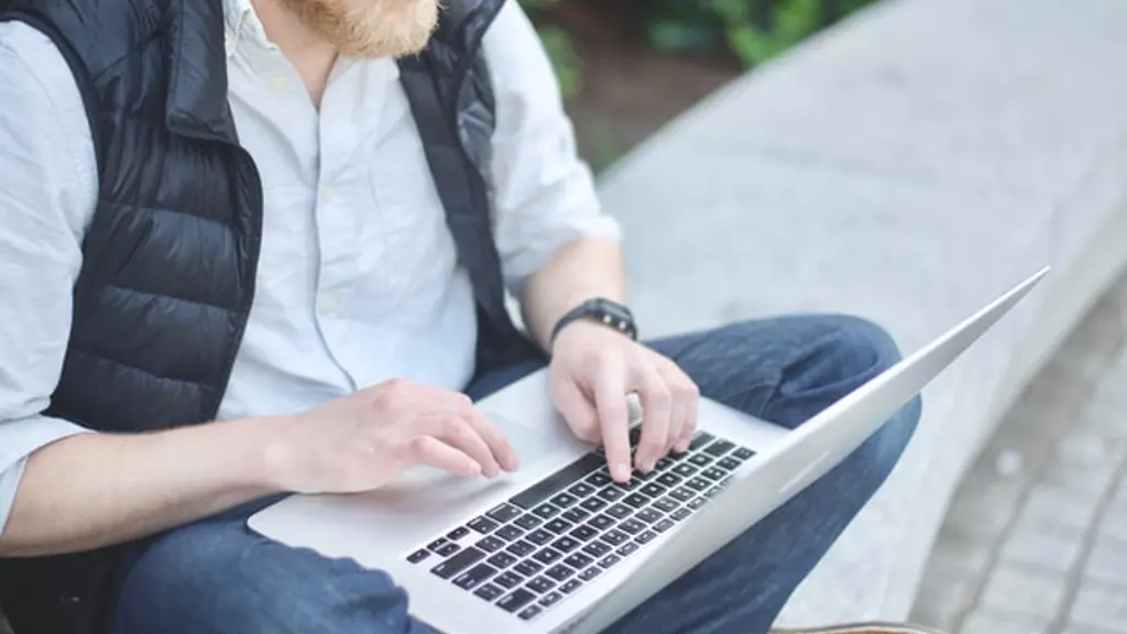 a man sitting on a stone bench using a laptop