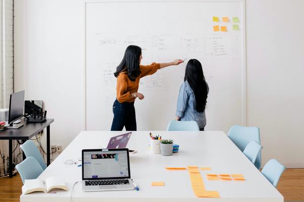 a woman pointing at a whiteboard