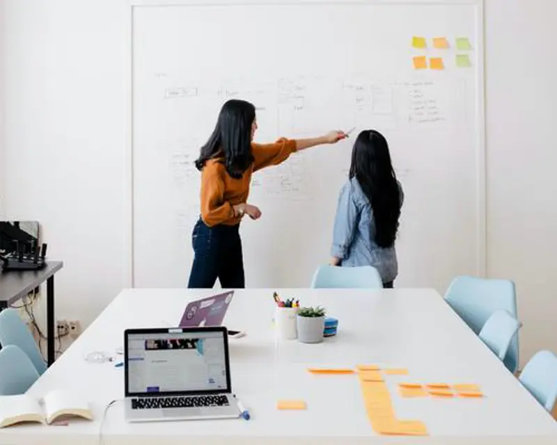 a woman pointing at a whiteboard