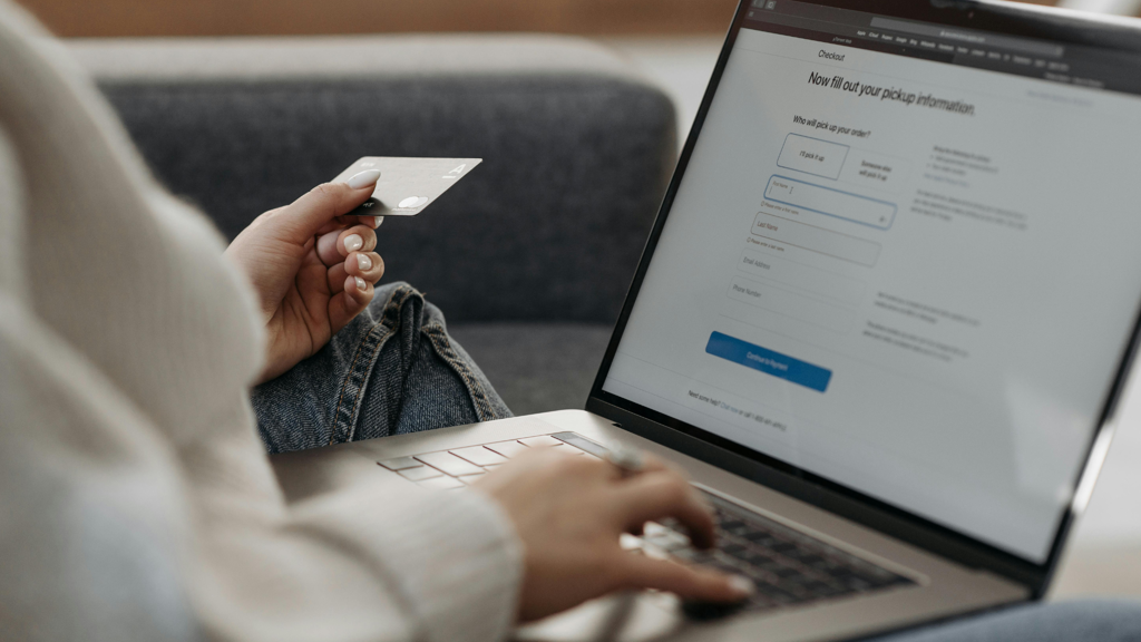 a person holding a credit card and typing on a laptop