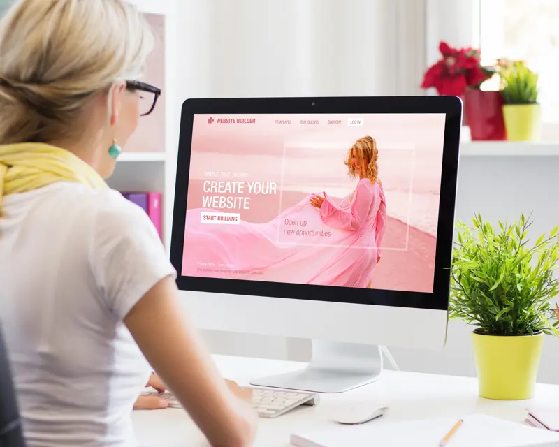 a woman sitting at a desk looking at a computer screen