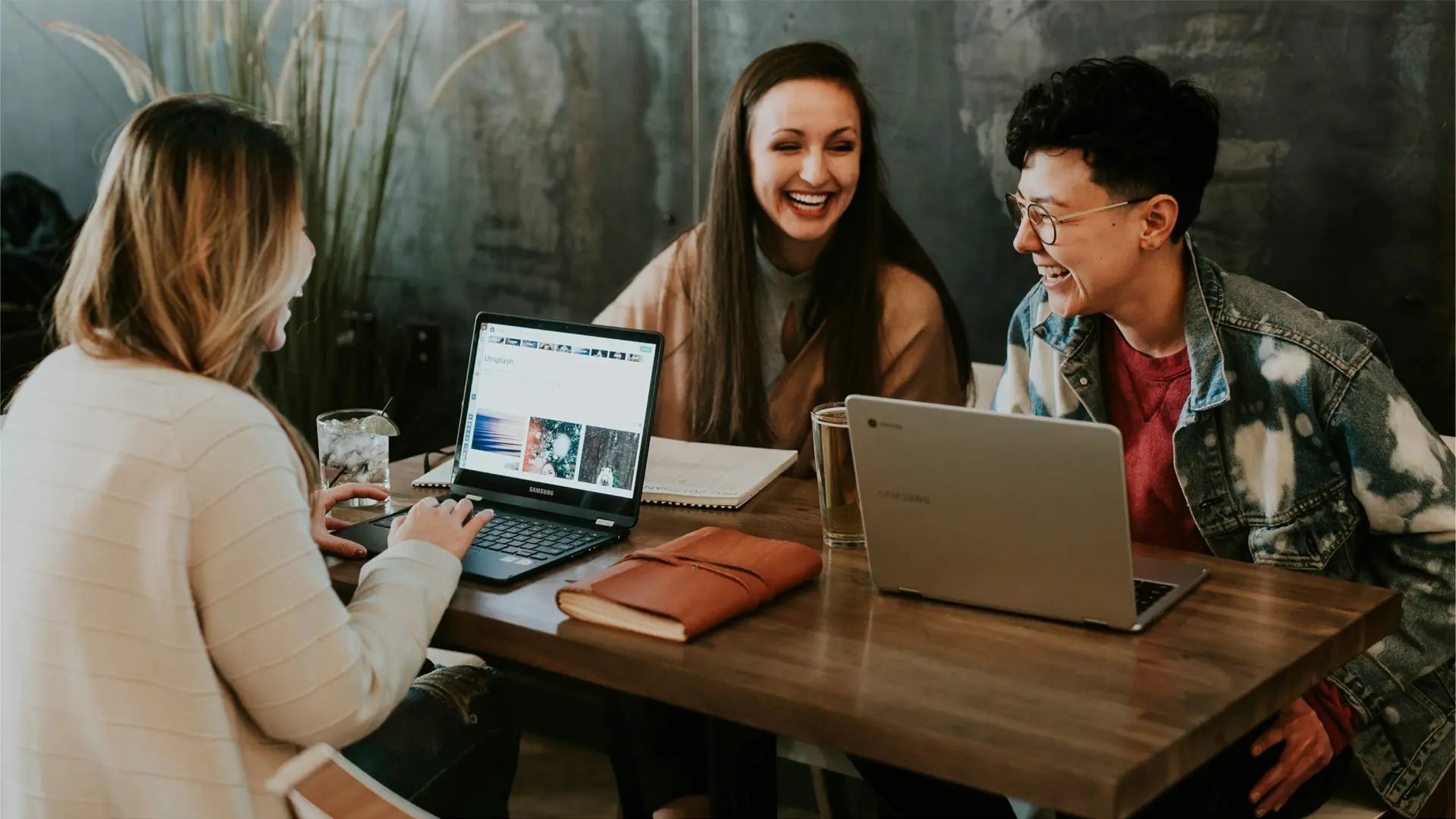 a group of people sitting at a table with laptops