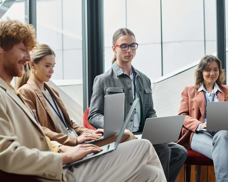 a group of people sitting in a circle using laptops