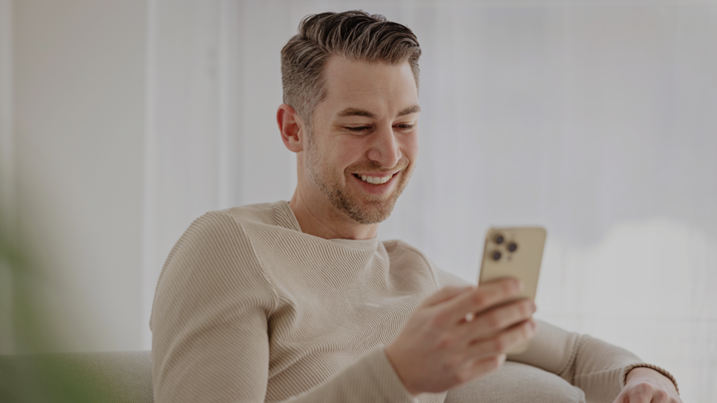 a man smiling while looking at his phone