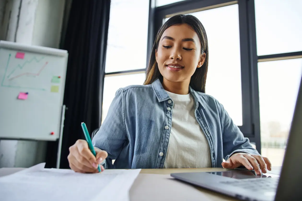 a woman sitting at a desk writing on a paper