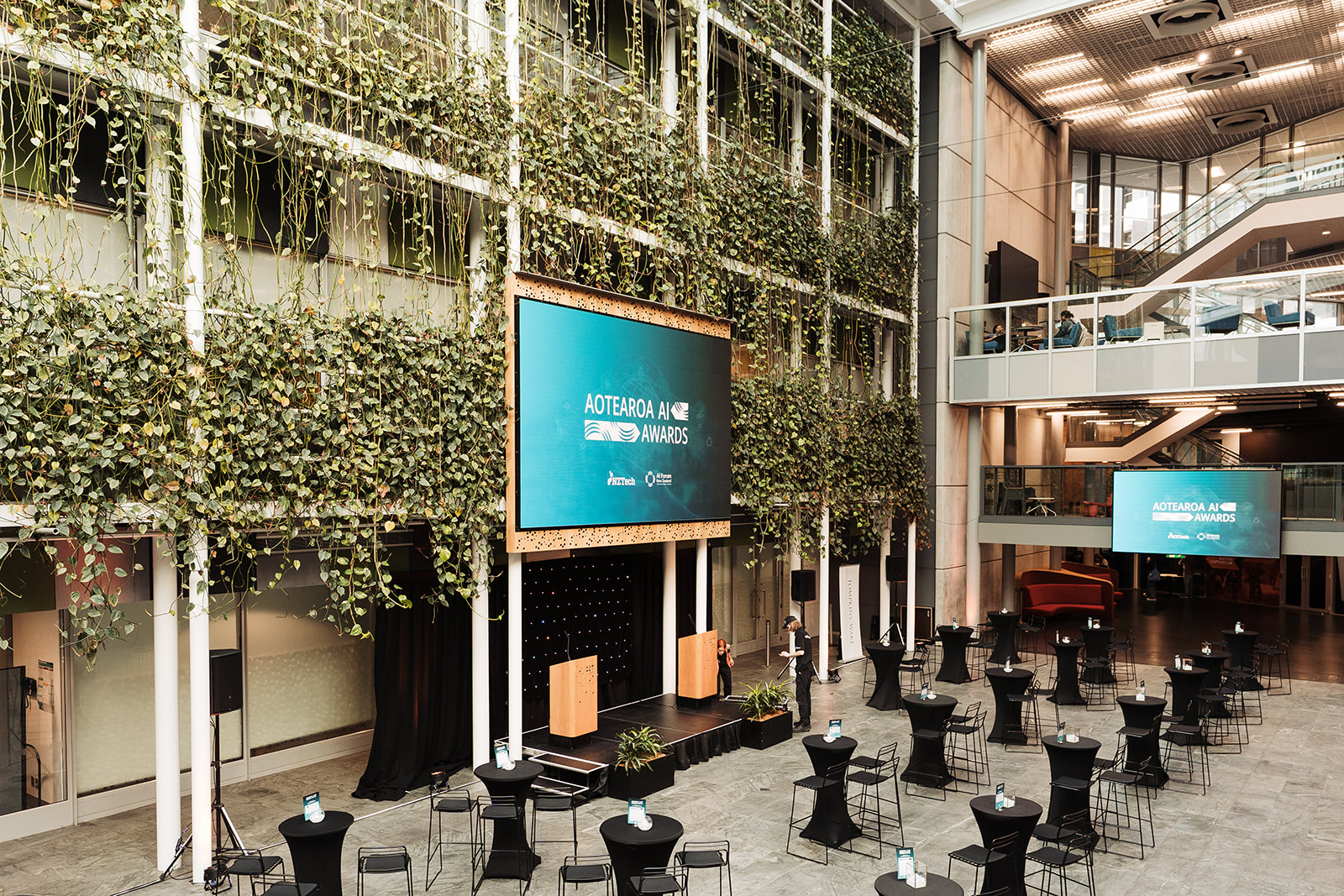 a room with tables and chairs and a screen on the wall