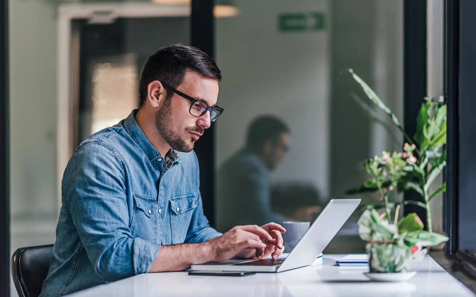 a man sitting at a desk using a laptop