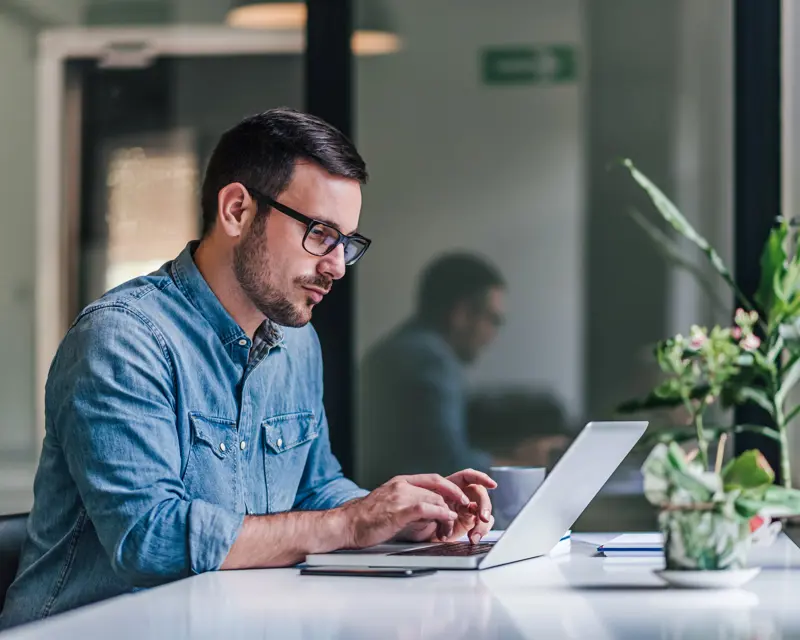 a man sitting at a desk using a laptop
