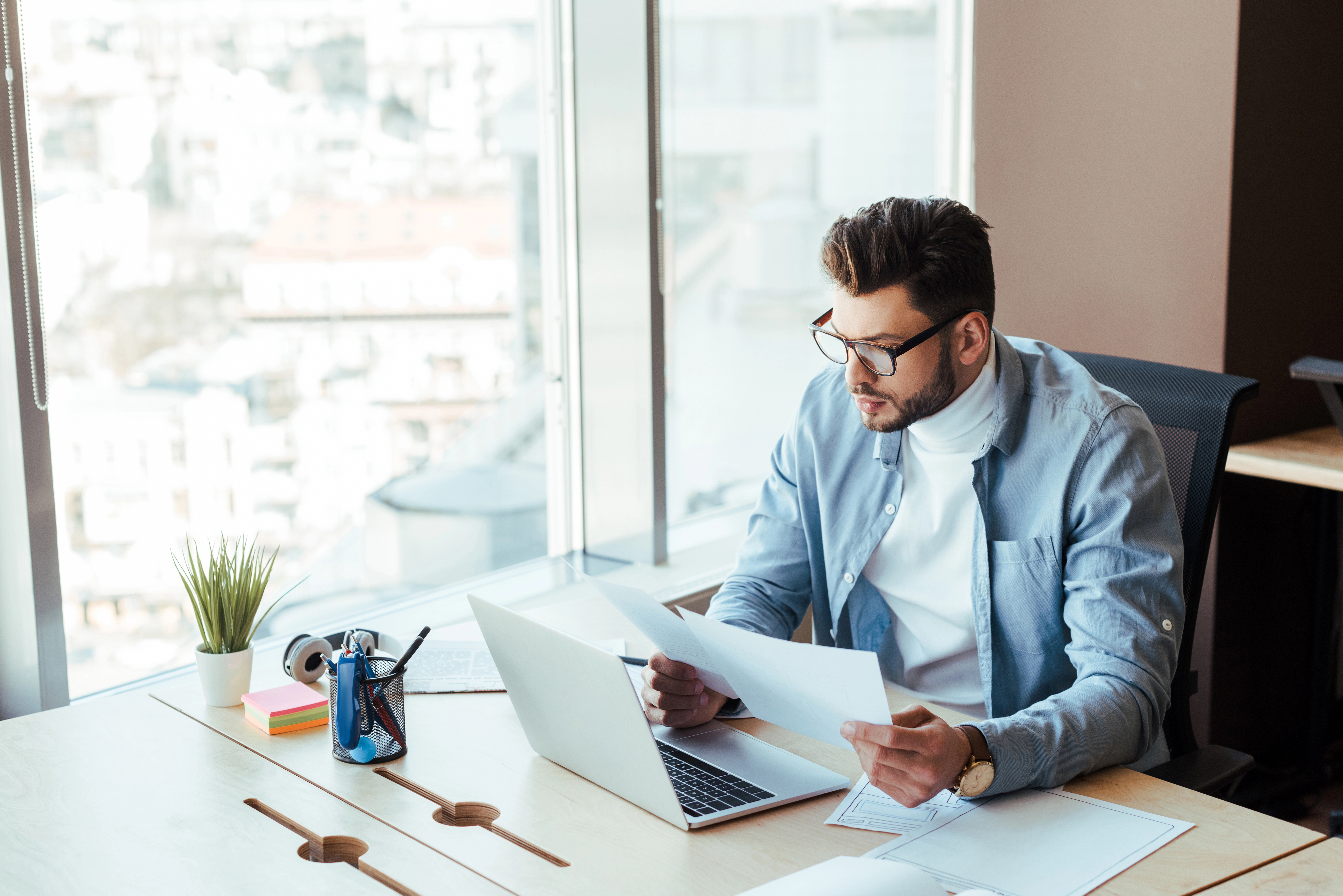 a man sitting at a desk with a laptop and papers