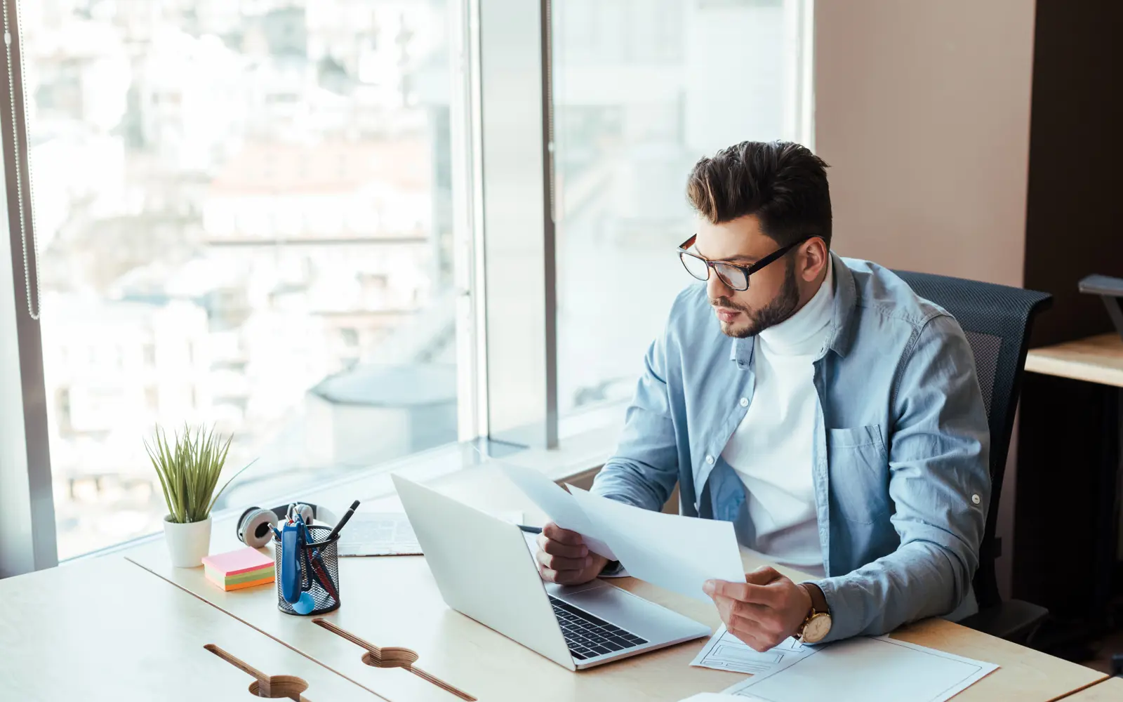 a man sitting at a desk with a laptop and papers