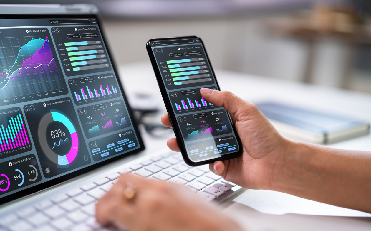 a person holding a phone and using a laptop