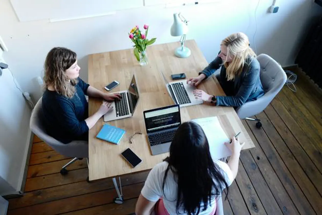 a group of women sitting at a table with laptops