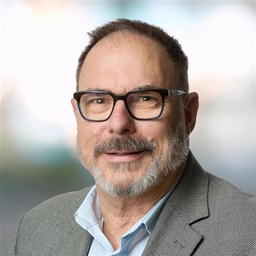 a man wearing glasses and a grey suit